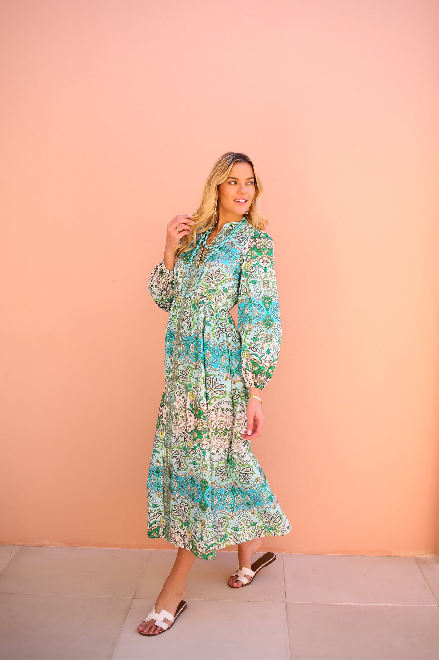 Woman wearing a floral dress against a peach-colored wall