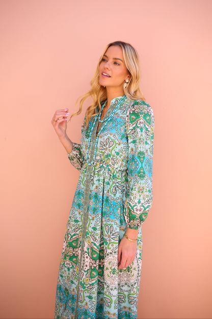 Woman wearing a patterned dress against a pink background