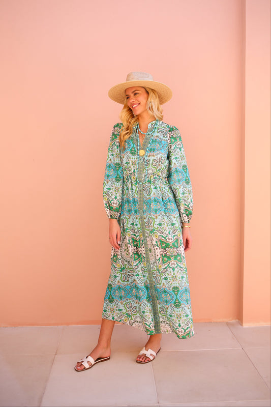 Woman wearing a floral dress and hat against a pink wall